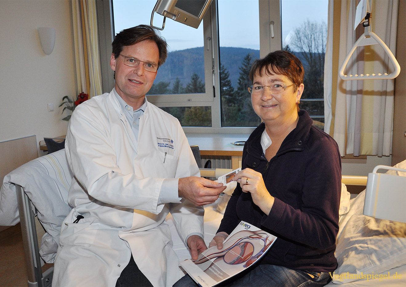 Dr. med. Jürgen Heyne übergibt Patientin Carmen Müller den Info-Patientenpass